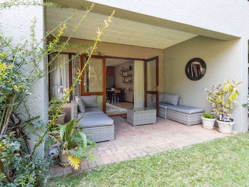 A covered patio area featuring paved flooring and timber-framed glass doors providing seamless access to the interior living space.