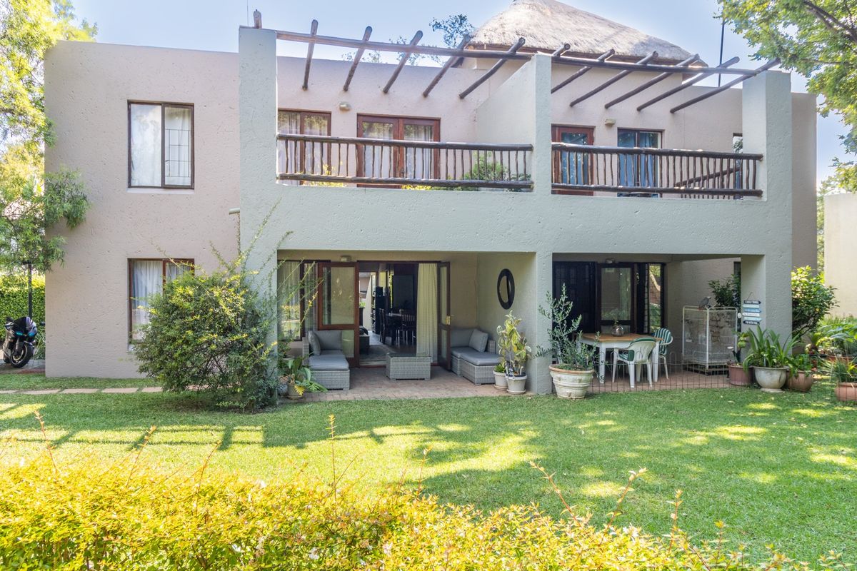 Rear view of the apartment featuring a ground floor covered patio, an upper balcony with timber balustrades, and a private garden area.