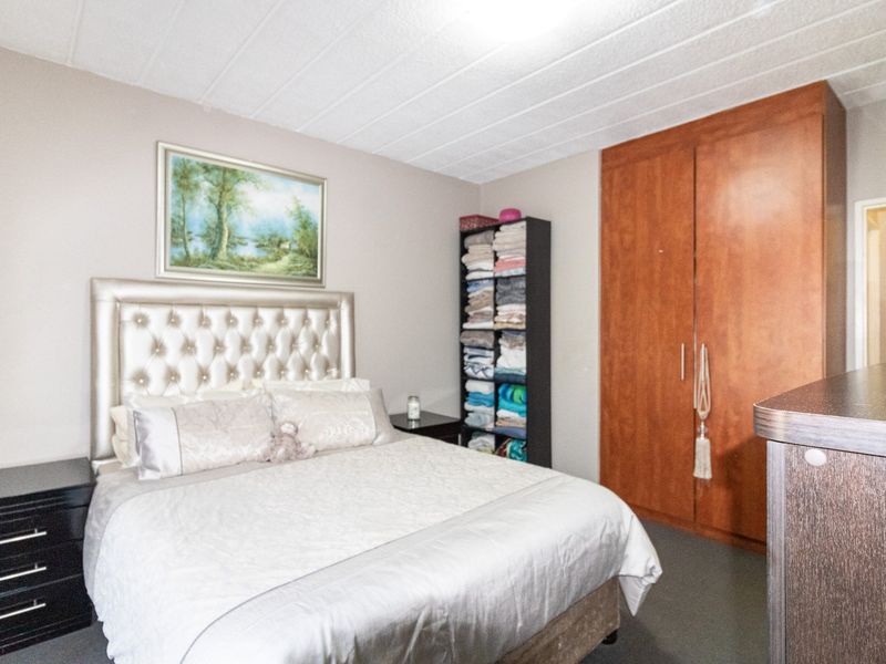 A bedroom featuring a built-in wooden wardrobe and a textured ceiling, providing functional storage space within the apartment.
