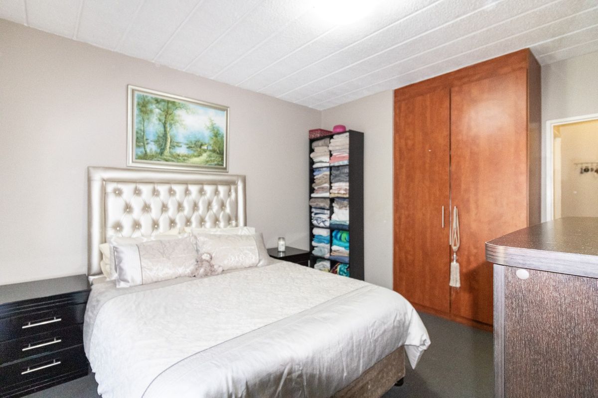 A bedroom featuring a built-in wooden wardrobe and a textured ceiling, providing functional storage space within the apartment.