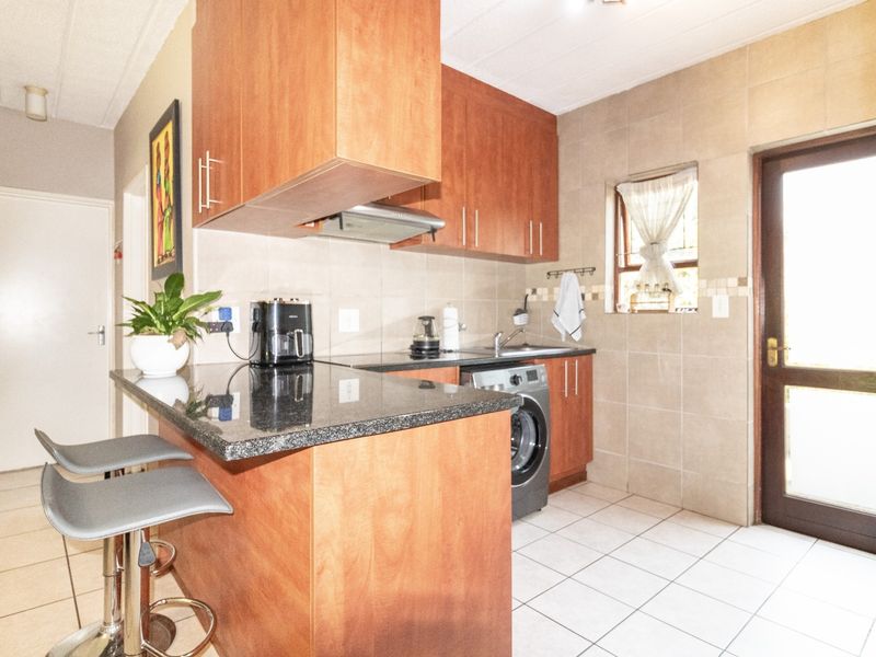 Compact kitchen featuring wooden cabinetry, granite countertops, tiled backsplash, and direct access to an external door.
