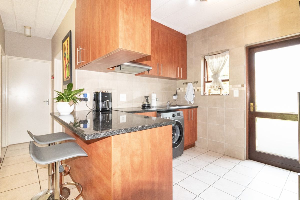 Compact kitchen featuring wooden cabinetry, granite countertops, tiled backsplash, and direct access to an external door.