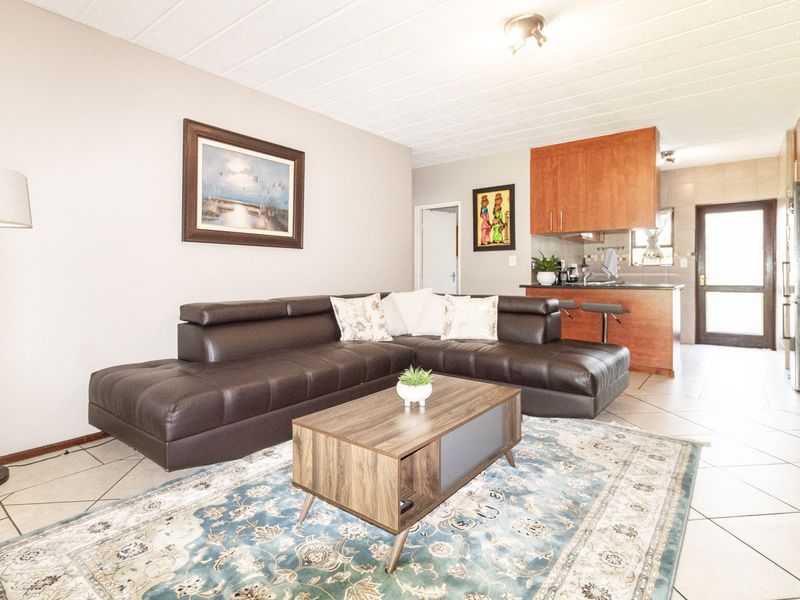 Open-plan living area featuring tiled flooring and a functional kitchen with wooden cabinetry and a breakfast counter.