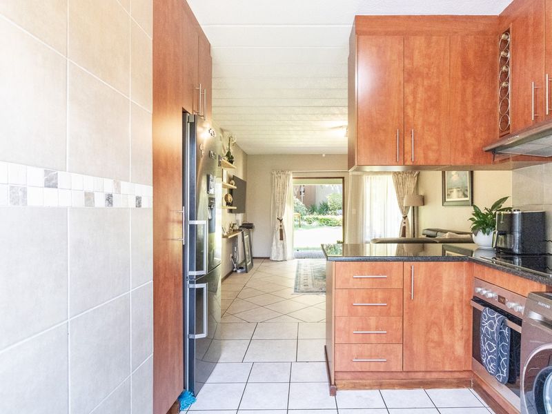 Open-plan kitchen featuring wood-finish cabinetry, granite countertops, and integrated appliances, flowing seamlessly into the living area with direct access to the outdoor space.