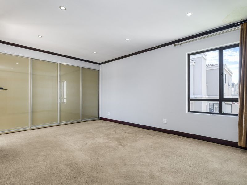 Spacious bedroom featuring built-in sliding door cupboards, recessed downlighting, and carpeted flooring, offering a clean and neutral canvas for personalization.