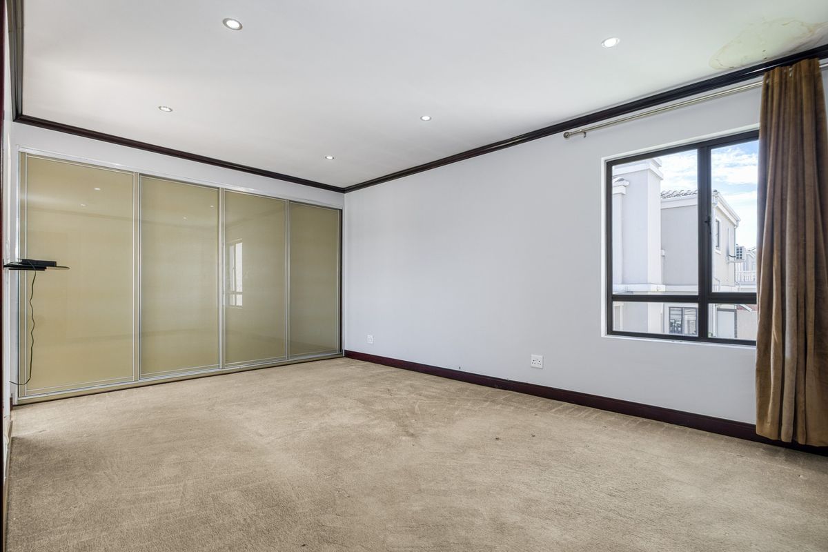 Spacious bedroom featuring built-in sliding door cupboards, recessed downlighting, and carpeted flooring, offering a clean and neutral canvas for personalization.