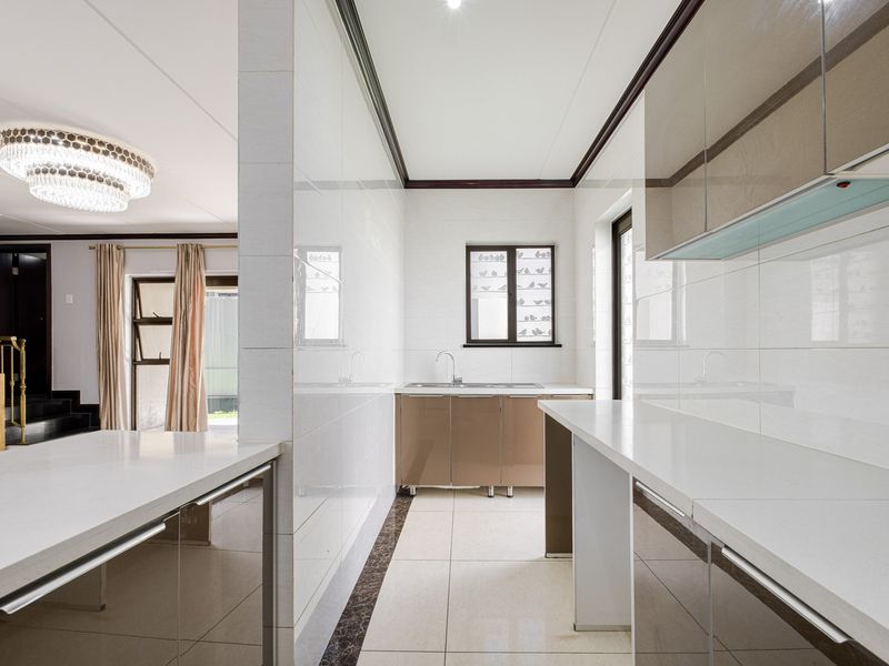A modern, clean kitchen featuring sleek cabinetry, stone countertops, and tiled finishes, offering a bright and functional workspace.