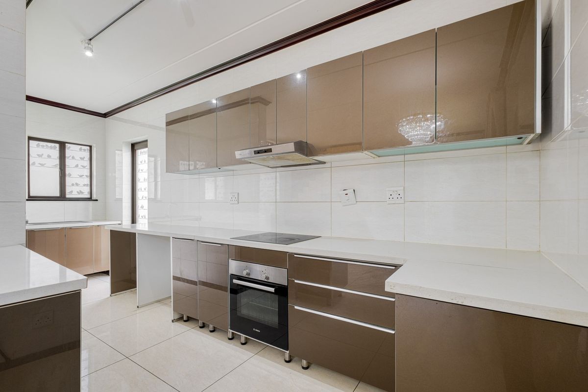 Modern kitchen featuring high-gloss cabinetry, stone countertops, built-in oven, electric hob, and extractor fan, complemented by neutral tiled flooring and backsplash.
