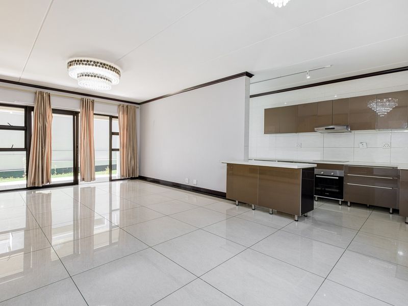 Spacious open-plan living and kitchen area featuring high-gloss cabinetry, modern tiled flooring, and large sliding doors leading to the exterior.