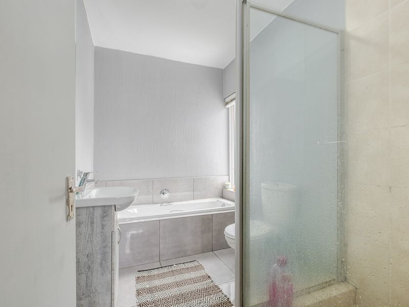 A clean, modern bathroom featuring a built-in bathtub, a separate shower enclosure with glass door, a vanity basin, and a toilet.