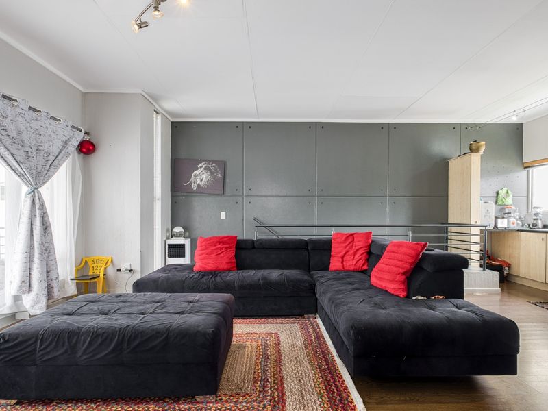 Open plan living area featuring a modern grey feature wall, laminate flooring, and direct access to a balcony through sliding glass doors.