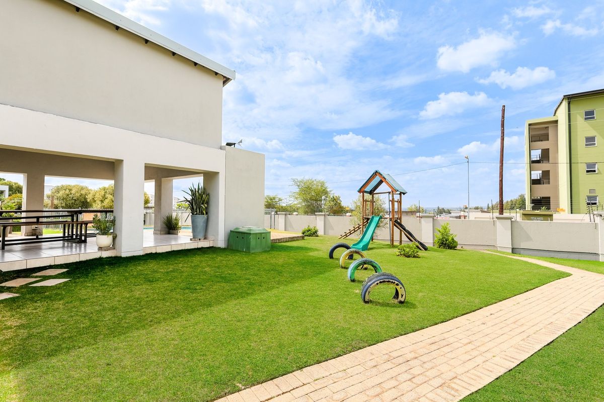 A well-maintained rear garden featuring a covered patio, paved walkway, and lawn area, providing a pleasant outdoor space for the apartment.