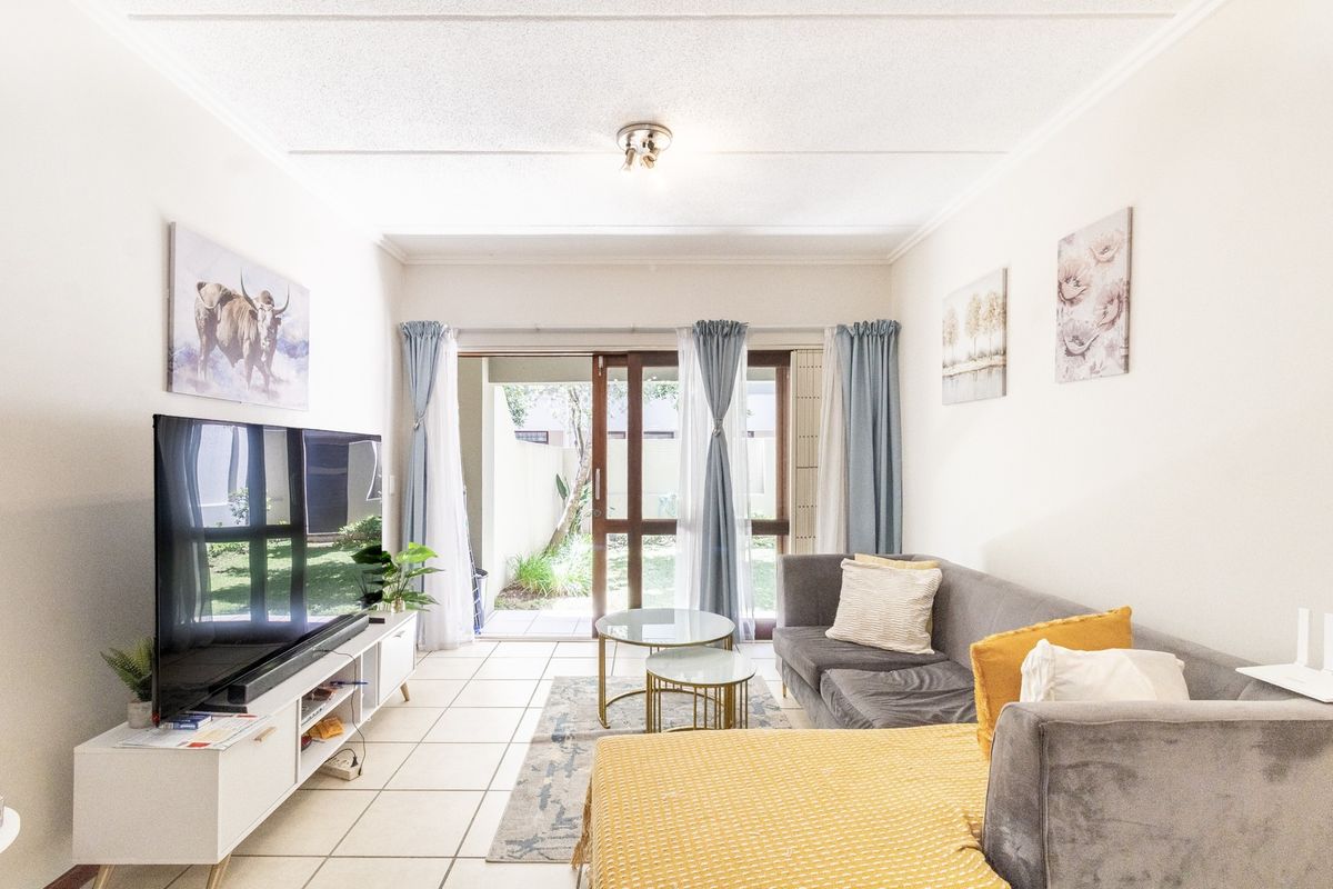 A bright living room featuring tiled flooring and a sliding glass door providing direct access to the outdoor patio area.