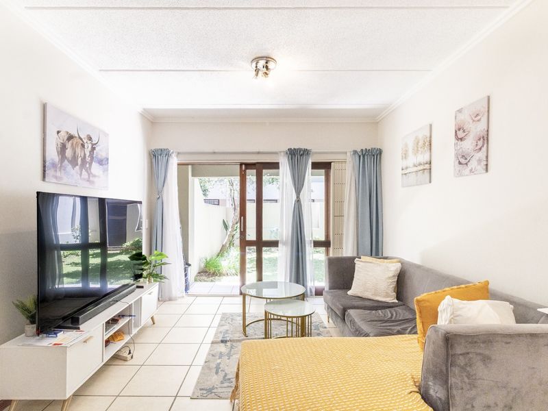 A bright living room featuring tiled flooring and a sliding glass door providing direct access to the outdoor patio area.