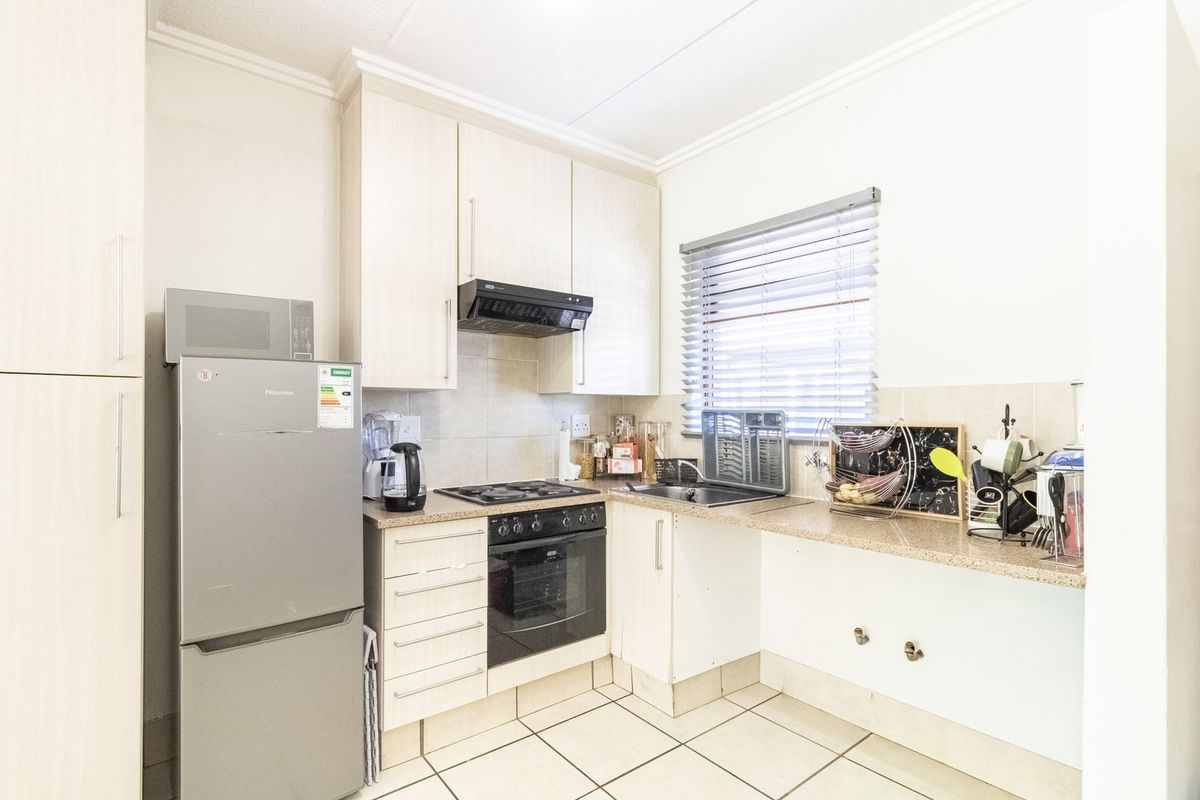 A functional kitchen featuring light-toned cabinetry, granite-look laminate countertops, a built-in oven with gas hob, and tiled flooring.