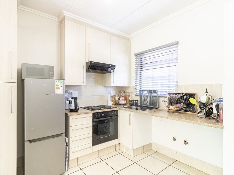 A functional kitchen featuring light-toned cabinetry, granite-look laminate countertops, a built-in oven with gas hob, and tiled flooring.