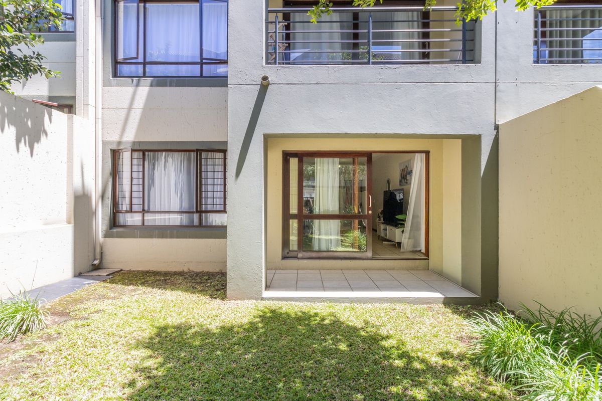 Rear view of the apartment featuring a small tiled patio, a sliding glass door entrance, and a private lawn area.