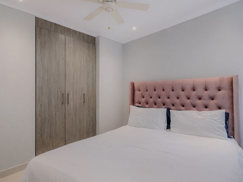 A well-maintained bedroom featuring modern built-in cupboards, a ceiling fan, and recessed lighting, offering a clean and contemporary living space.