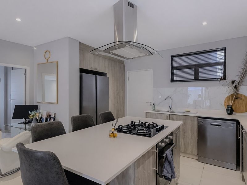 Modern kitchen featuring a central island with a gas hob, built-in oven, stainless steel extractor fan, and sleek cabinetry with marble-look splashback.