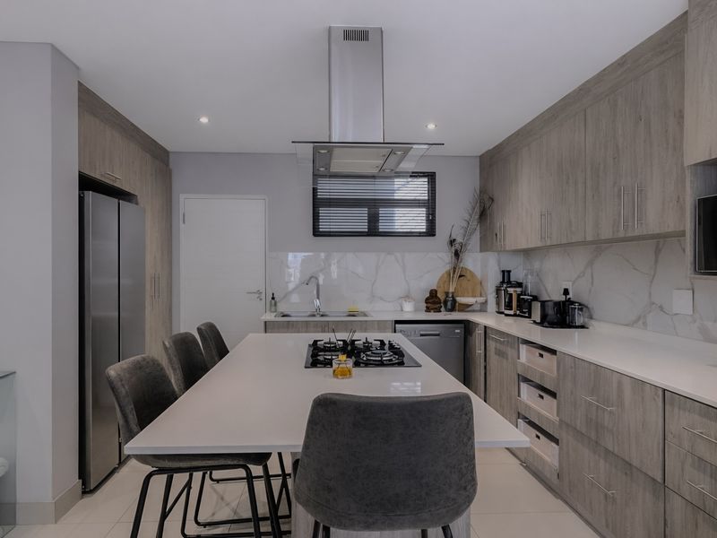 Modern kitchen featuring wood-grain cabinetry, stone countertops, a central island with a gas hob, and high-end integrated appliances.