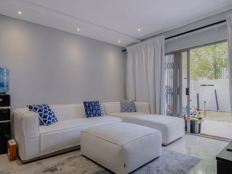 A bright living room featuring tiled floors, recessed lighting, and a sliding glass door providing access to an outdoor patio area.