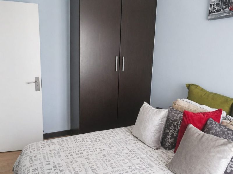 A bedroom featuring a dark wood built-in wardrobe and light blue walls.