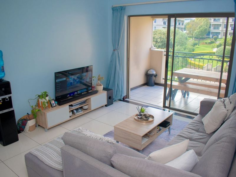 A living room featuring light-colored tiled flooring and a sliding glass door that provides access to an outdoor balcony area.