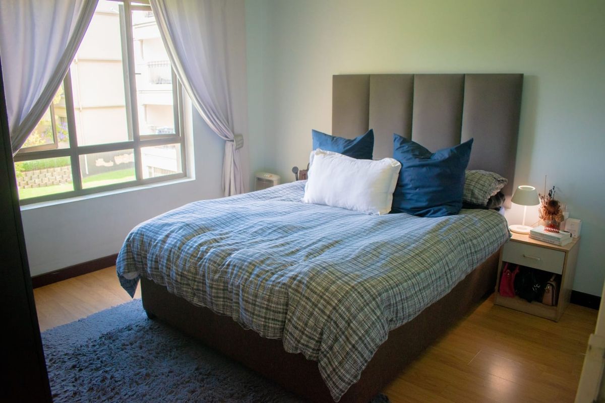 A well-lit bedroom featuring laminate flooring and a large window providing natural light.