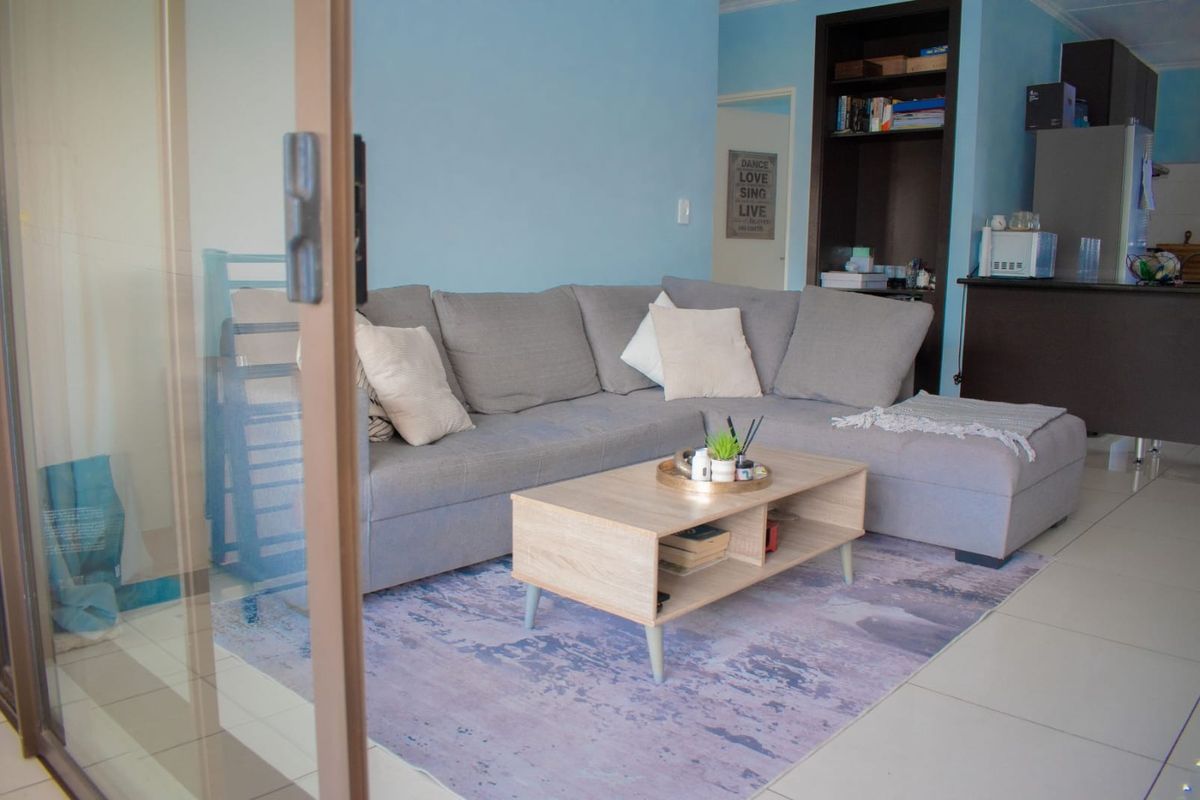 A living room area featuring tiled flooring, a built-in shelving unit, and access to an outdoor space via a sliding glass door.