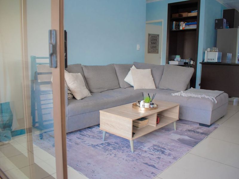 A living room area featuring tiled flooring, a built-in shelving unit, and access to an outdoor space via a sliding glass door.
