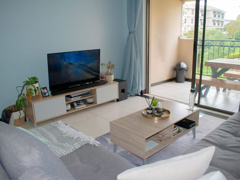 A bright living room featuring tiled flooring and large sliding glass doors that provide seamless access to an outdoor balcony area.