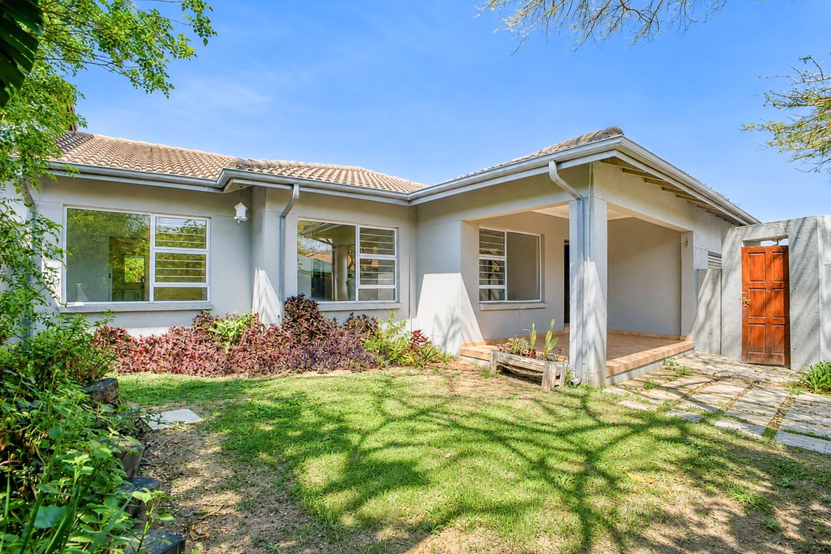 Rear view of the townhouse featuring a covered patio, tiled roof, and a private garden area with paved access.