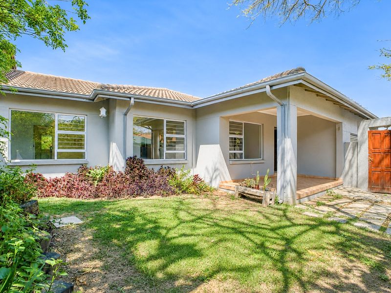 Rear view of the townhouse featuring a covered patio, tiled roof, and a private garden area with paved access.
