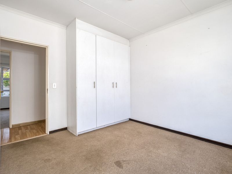 An empty bedroom featuring neutral walls, carpet flooring, and a built-in wardrobe, offering a blank canvas for personalization.