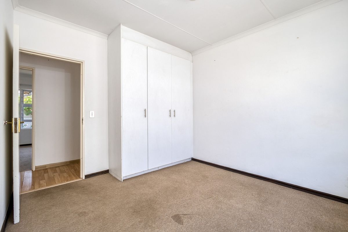 An empty bedroom featuring neutral walls, carpet flooring, and a built-in wardrobe, offering a blank canvas for personalization.