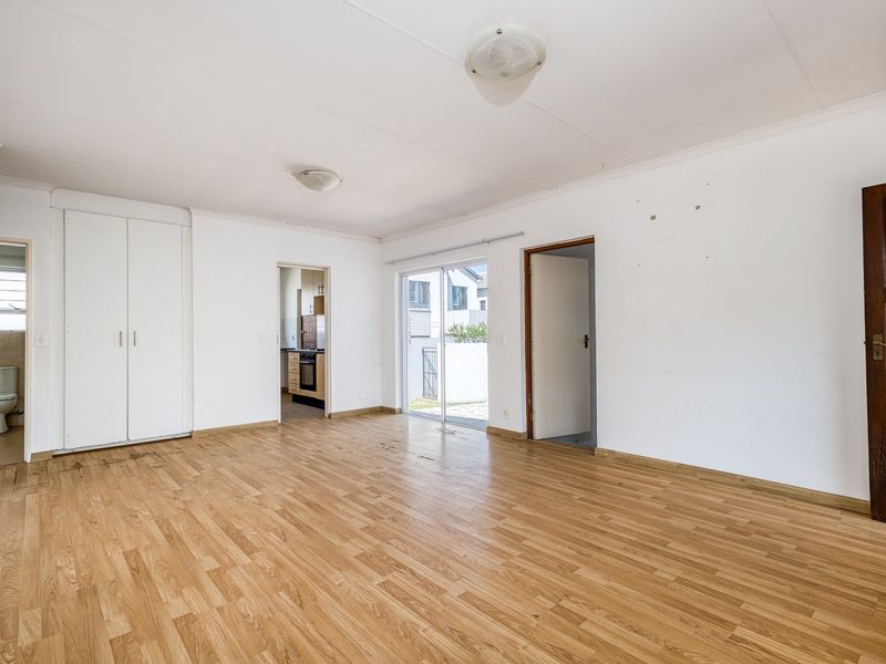 Spacious, empty living area featuring laminate flooring, built-in cupboards, and direct access to an outdoor patio through a sliding glass door.