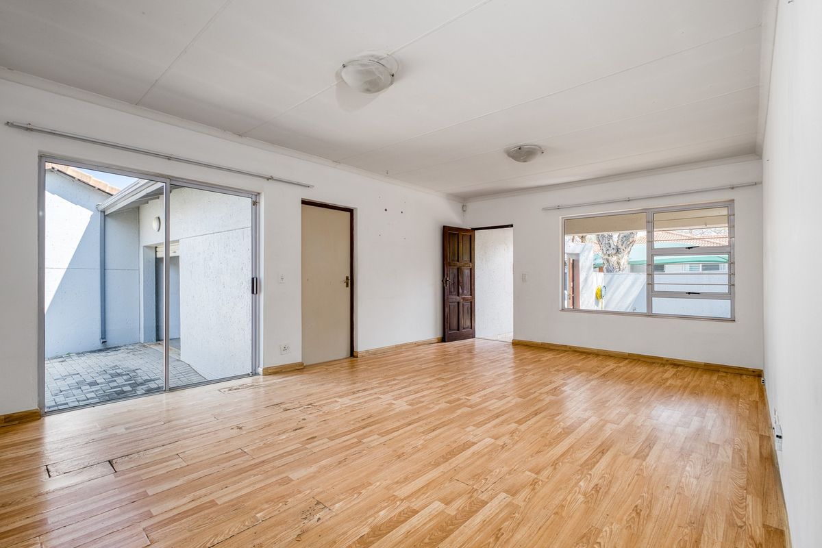 Spacious, empty living area featuring laminate flooring, large sliding glass doors leading to an outdoor patio, and ample natural light.