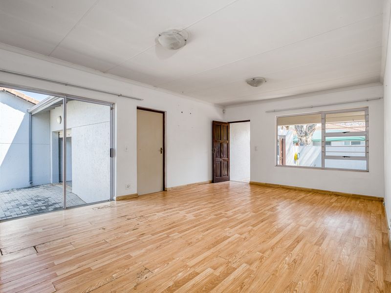 Spacious, empty living area featuring laminate flooring, large sliding glass doors leading to an outdoor patio, and ample natural light.
