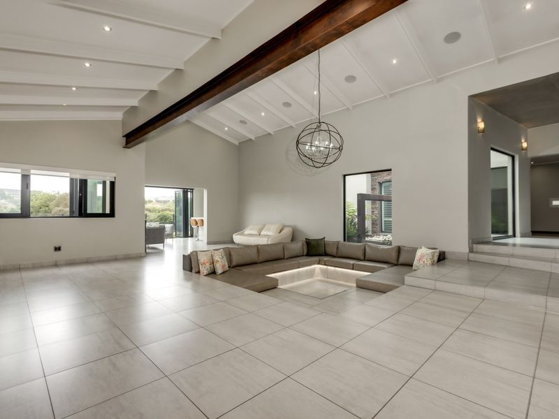 Spacious living area featuring a unique sunken conversation pit, vaulted ceilings with exposed timber beams, and large bi-fold doors opening to the outdoors.