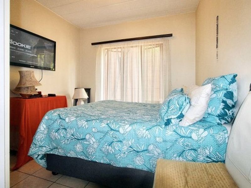 A functional bedroom featuring tiled flooring and a window with a curtain rod, providing a neutral base for potential interior updates.