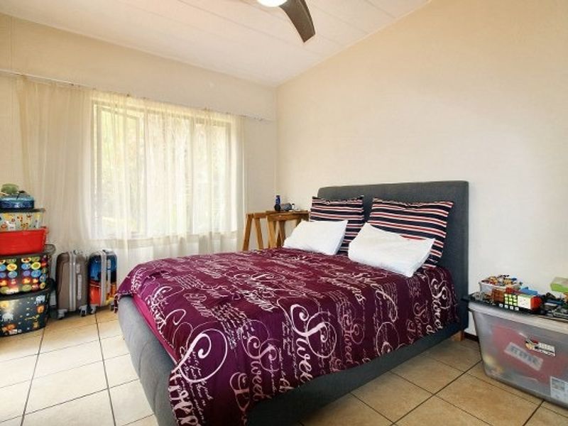 A functional bedroom featuring tiled flooring and a ceiling fan, offering a neutral base for personalization.