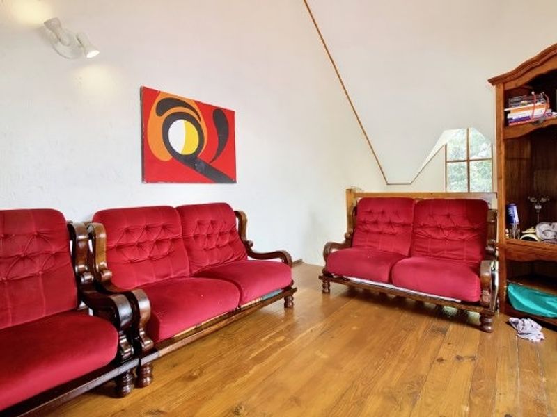 A living room area featuring polished timber flooring and a distinctive sloped ceiling, providing a unique architectural character to the space.