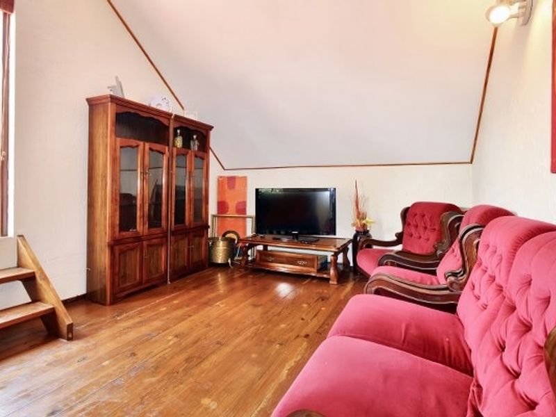 A living room featuring hardwood flooring and a sloped ceiling, providing a cozy atmosphere with potential for modern updates.