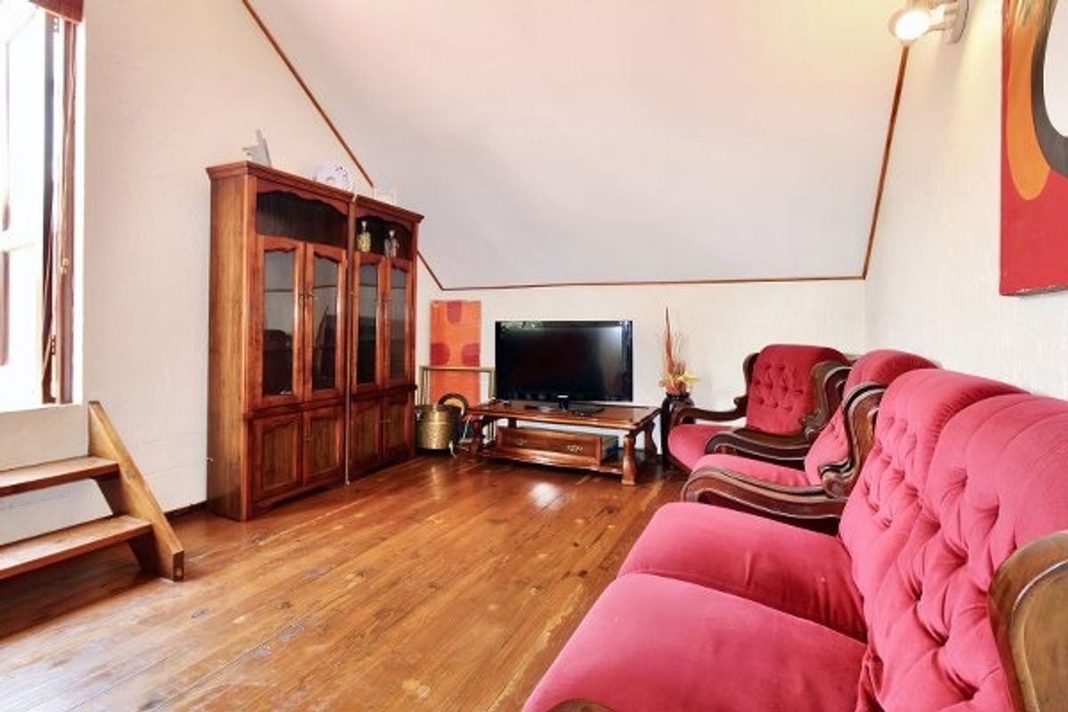 A living room featuring hardwood flooring and a sloped ceiling, providing a cozy atmosphere with potential for modern updates.