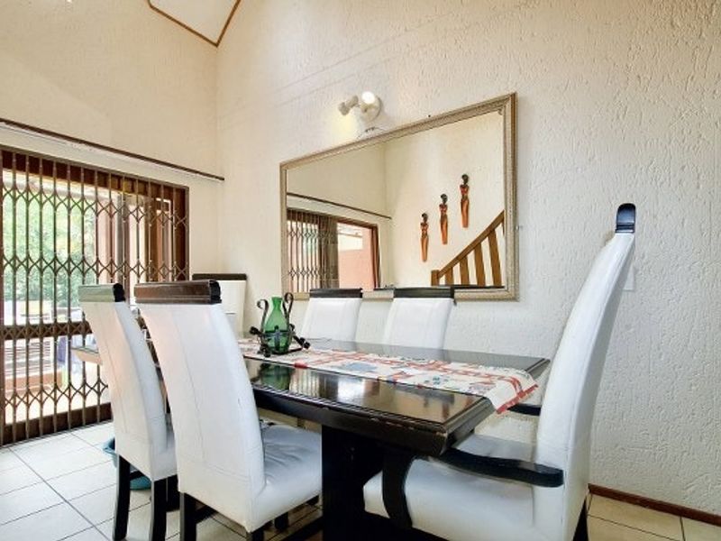 Dining area featuring tiled flooring, a vaulted ceiling, and a security gate leading to the exterior.