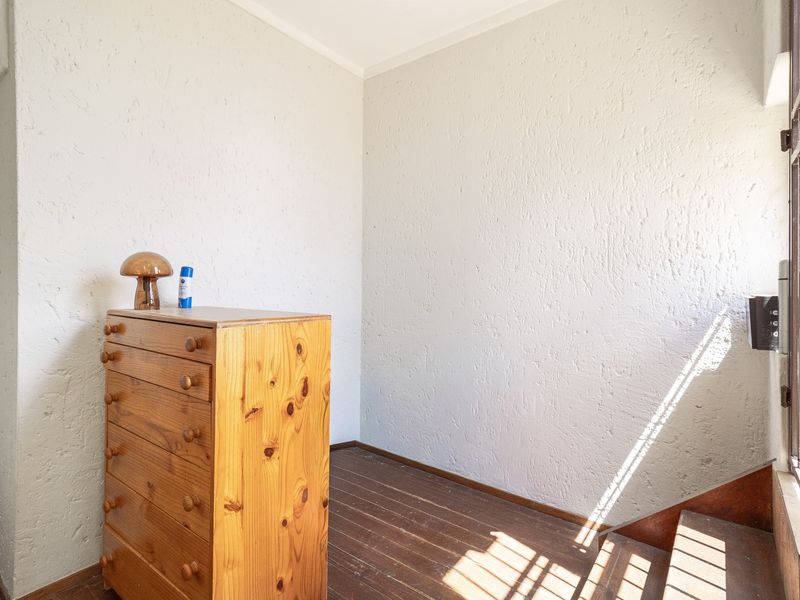 A bedroom space featuring textured walls and original timber flooring, offering a blank canvas for renovation or interior design updates.