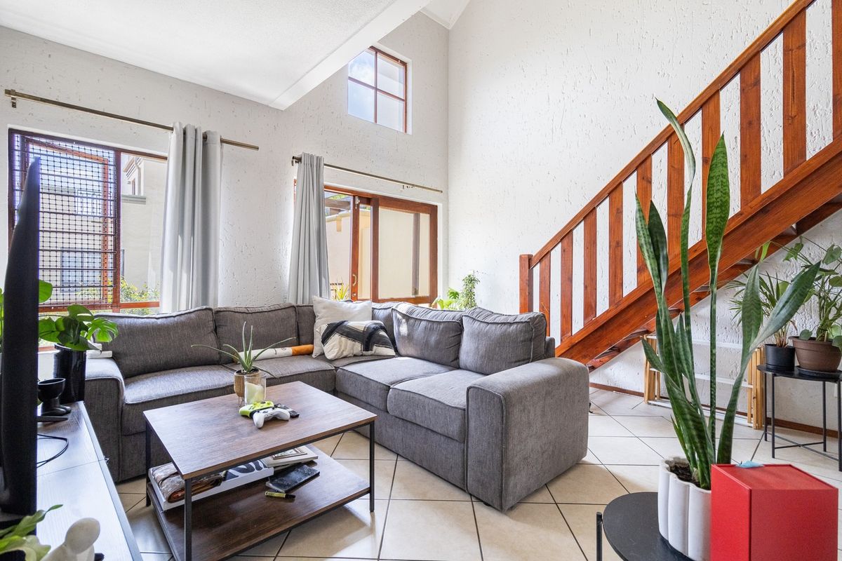 Spacious living room featuring high vaulted ceilings, a wooden staircase, and large windows that provide ample natural light.