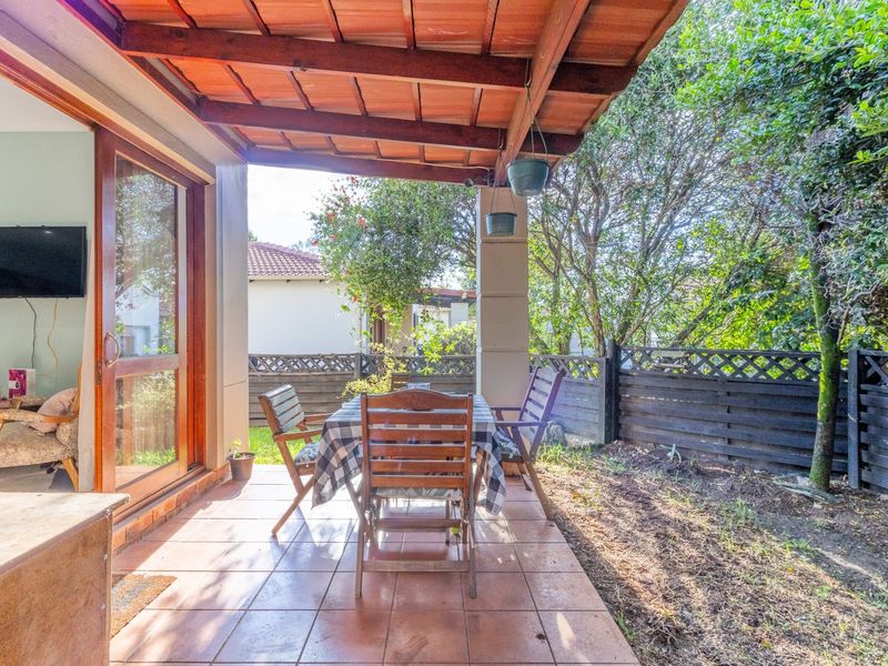 Covered patio area featuring tiled flooring and a timber roof structure, providing direct access to the garden through a sliding glass door.