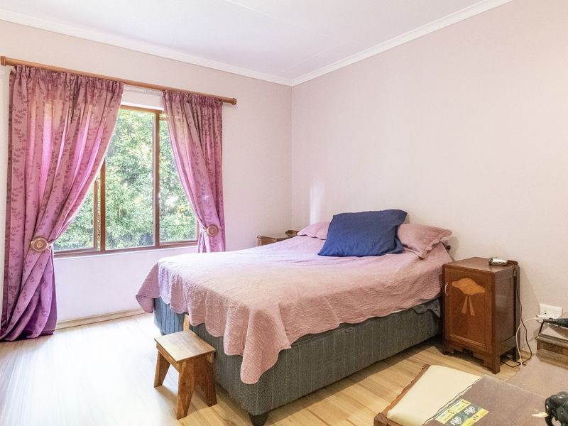 A bedroom featuring laminate flooring and a window with a curtain rod, offering a neutral space ready for personalization.