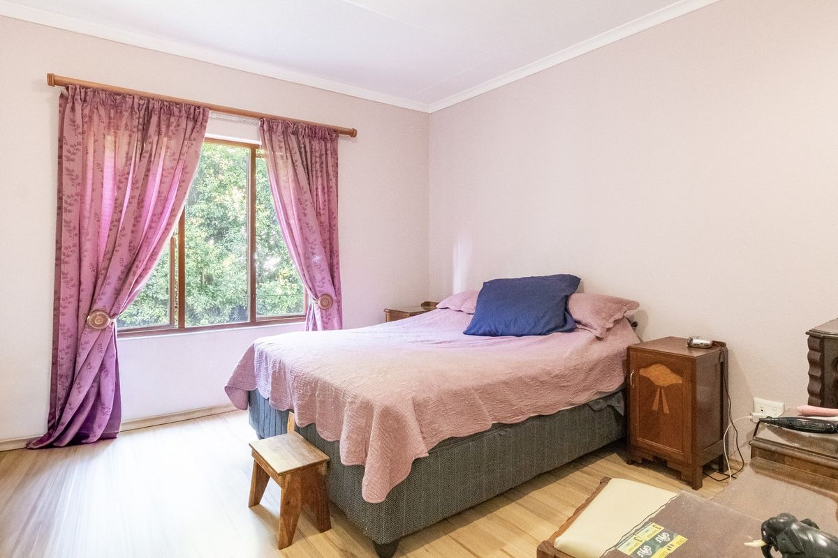 A bedroom featuring laminate flooring and a window with a curtain rod, offering a neutral space ready for personalization.